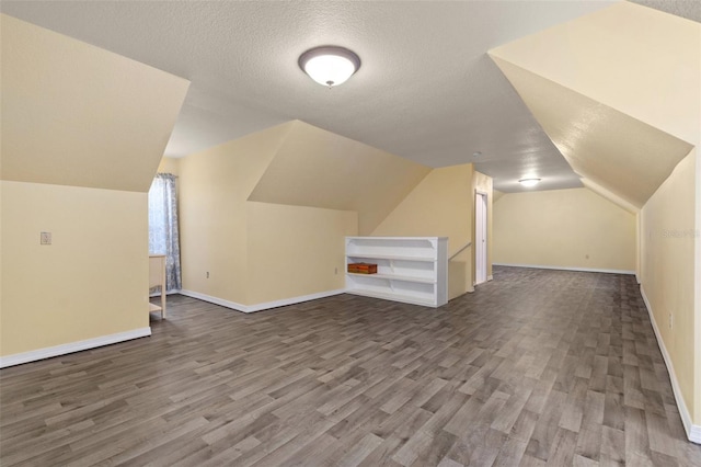 bonus room with wood-type flooring, a textured ceiling, and lofted ceiling