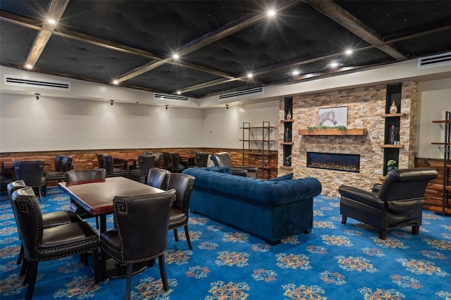 interior space featuring coffered ceiling, a stone fireplace, beam ceiling, and carpet floors