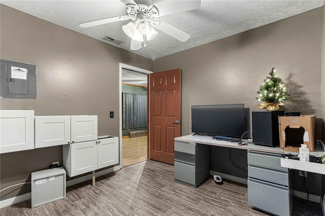 office area featuring light hardwood / wood-style floors, ceiling fan, built in desk, and a textured ceiling