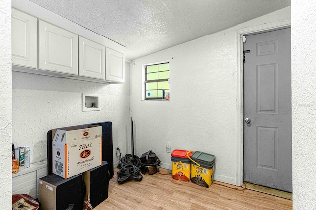 washroom with light hardwood / wood-style floors, cabinets, hookup for a washing machine, and a textured ceiling