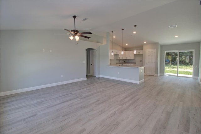 unfurnished living room with ceiling fan, high vaulted ceiling, sink, and light wood-type flooring