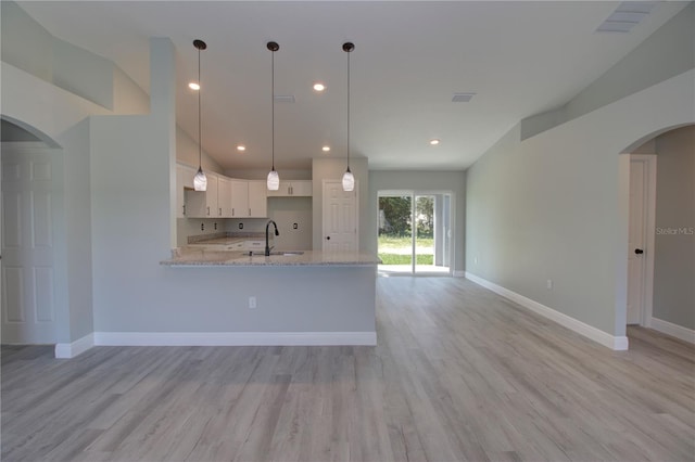 kitchen featuring white cabinets, light stone countertops, light hardwood / wood-style flooring, sink, and decorative light fixtures