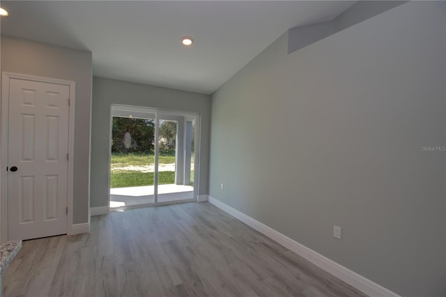 spare room featuring lofted ceiling and light hardwood / wood-style floors