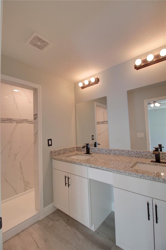 bathroom featuring vanity, tiled shower, and hardwood / wood-style floors