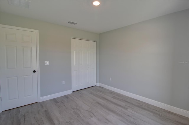 unfurnished bedroom with light hardwood / wood-style flooring and a closet