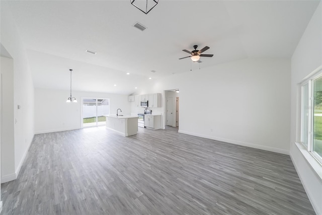 unfurnished living room with lofted ceiling, light wood-style flooring, ceiling fan with notable chandelier, and visible vents