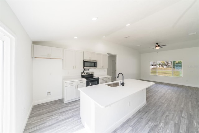 kitchen featuring electric stove, lofted ceiling, stainless steel microwave, light countertops, and a sink