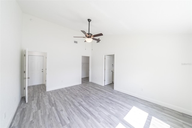 unfurnished room with high vaulted ceiling, light wood-style floors, a ceiling fan, and baseboards