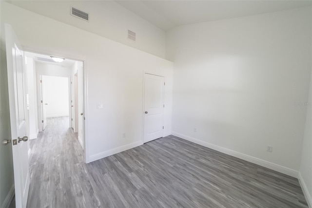 spare room with high vaulted ceiling, wood finished floors, visible vents, and baseboards