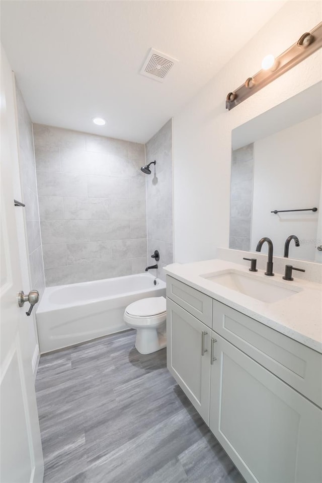 full bathroom with visible vents, shower / bathing tub combination, toilet, vanity, and wood finished floors