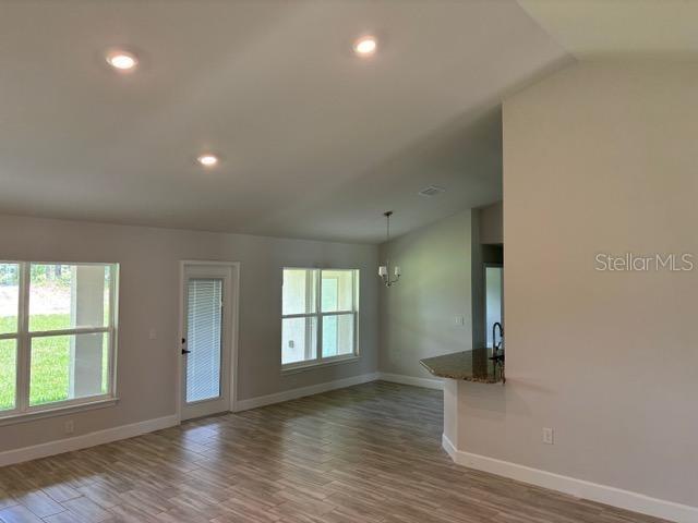 unfurnished room with vaulted ceiling, hardwood / wood-style floors, and a chandelier