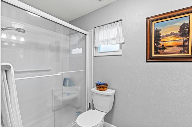 bathroom featuring toilet and a shower with shower door