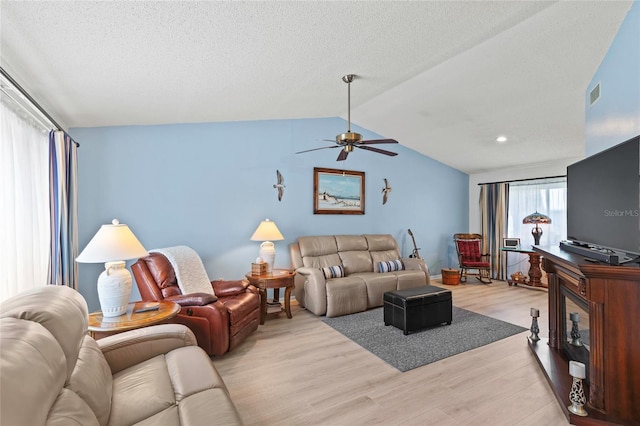 living room featuring ceiling fan, light hardwood / wood-style flooring, and vaulted ceiling