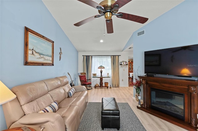 living room with ceiling fan, light hardwood / wood-style flooring, and vaulted ceiling