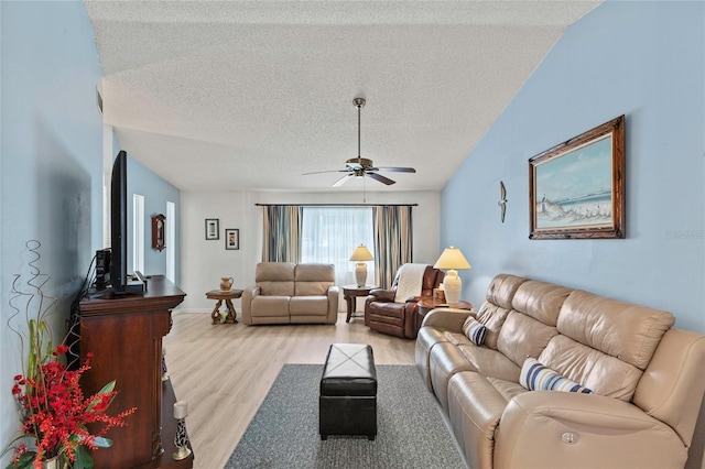 living room with ceiling fan, lofted ceiling, a textured ceiling, and light hardwood / wood-style flooring