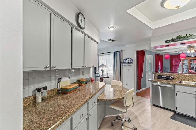 kitchen featuring dishwasher, light hardwood / wood-style flooring, kitchen peninsula, pendant lighting, and decorative backsplash