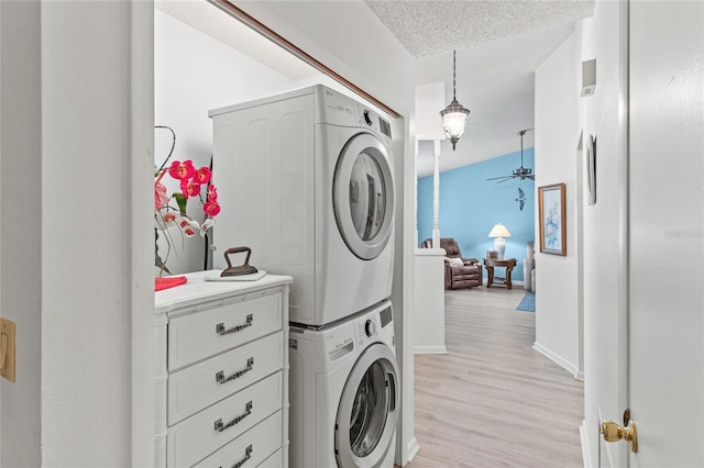 laundry room with a textured ceiling, light hardwood / wood-style flooring, ceiling fan, and stacked washer / drying machine