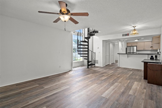 unfurnished living room featuring a textured ceiling, ceiling fan, and dark wood-type flooring