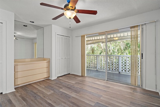 unfurnished bedroom with wood-type flooring, ceiling fan, access to exterior, and a textured ceiling