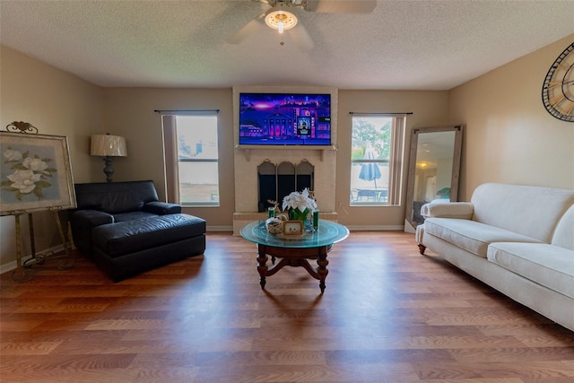 living room featuring hardwood / wood-style flooring, ceiling fan, and a textured ceiling