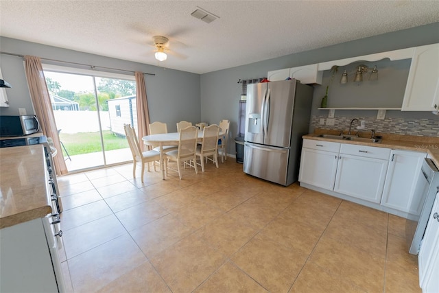 kitchen featuring appliances with stainless steel finishes, ceiling fan, sink, backsplash, and white cabinetry