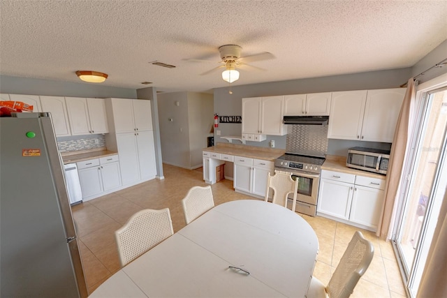 kitchen featuring white cabinetry, stainless steel appliances, light tile floors, tasteful backsplash, and ceiling fan