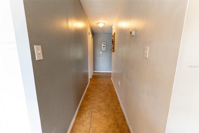 hall featuring tile flooring and a textured ceiling