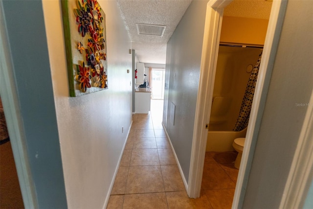 hallway with light tile floors and a textured ceiling