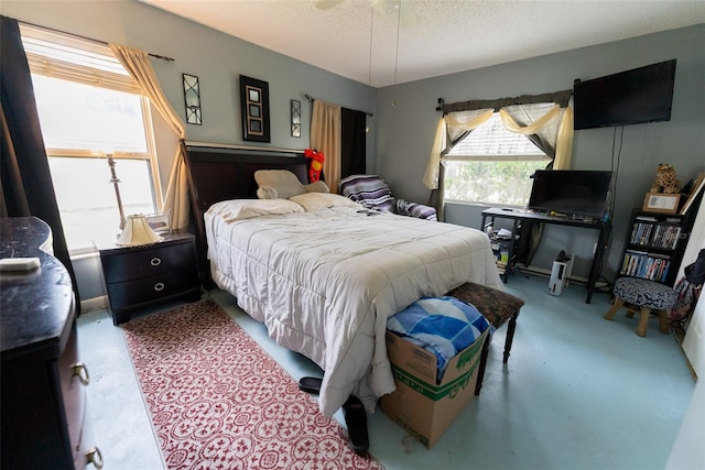 bedroom with ceiling fan, concrete floors, and a textured ceiling