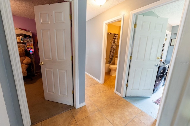 hallway featuring a textured ceiling and light tile floors