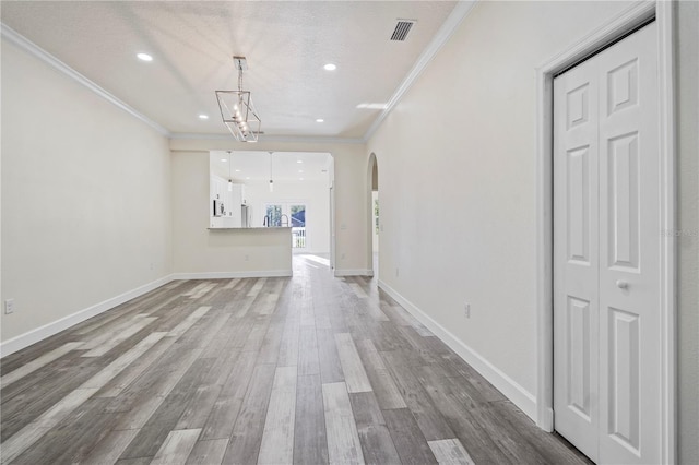 unfurnished living room featuring crown molding, wood-type flooring, a textured ceiling, and an inviting chandelier