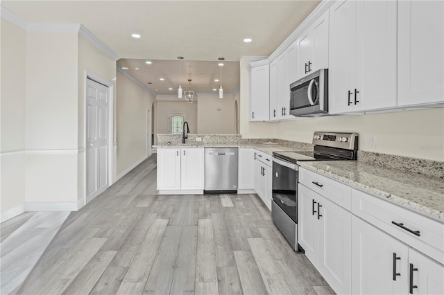 kitchen featuring kitchen peninsula, appliances with stainless steel finishes, ornamental molding, decorative light fixtures, and white cabinetry