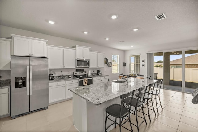 kitchen featuring white cabinets, appliances with stainless steel finishes, sink, and an island with sink