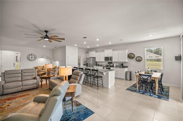 tiled living room featuring ceiling fan and a textured ceiling