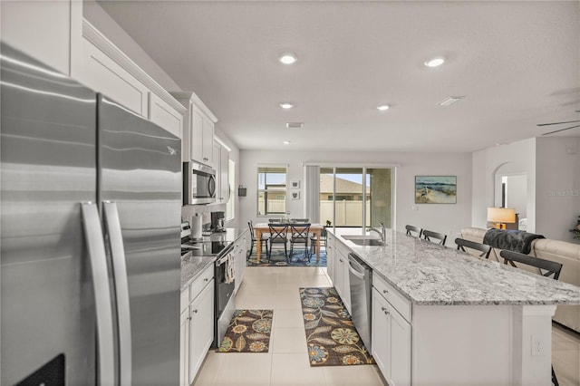 kitchen featuring a kitchen bar, appliances with stainless steel finishes, a center island with sink, and white cabinetry