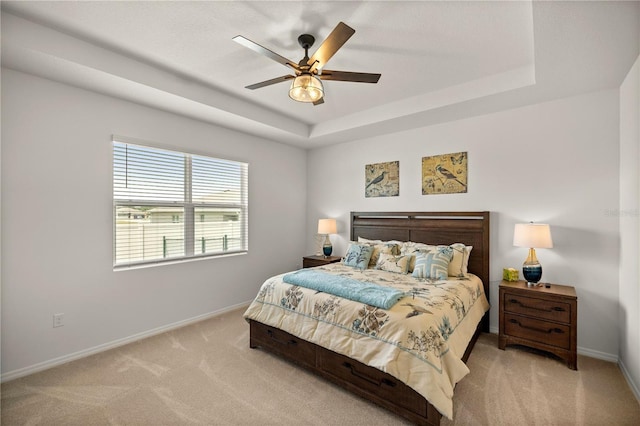 bedroom featuring a tray ceiling, ceiling fan, and light carpet