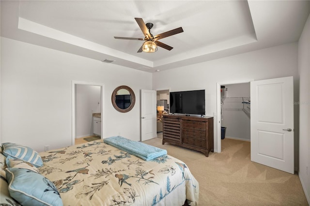 carpeted bedroom with a walk in closet, a closet, a raised ceiling, and ceiling fan