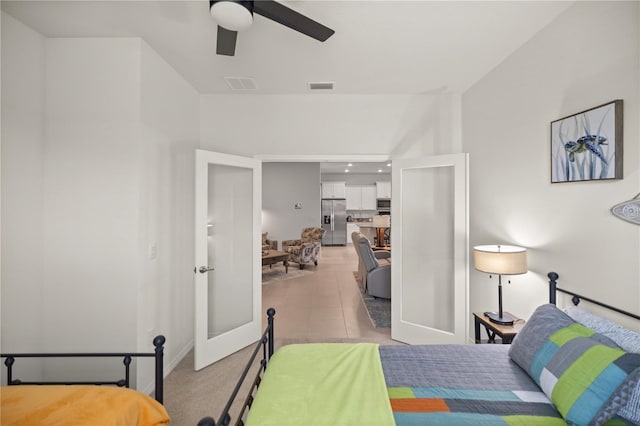 bedroom with stainless steel fridge, french doors, light tile patterned floors, and ceiling fan