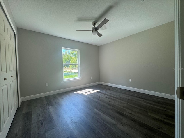 unfurnished bedroom with ceiling fan, dark hardwood / wood-style floors, a closet, and a textured ceiling