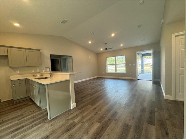 kitchen featuring sink, vaulted ceiling, dark hardwood / wood-style floors, gray cabinets, and kitchen peninsula