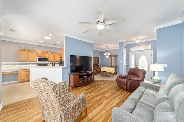 living room with ornamental molding, ceiling fan with notable chandelier, and light tile floors