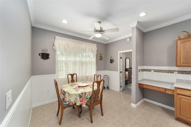 tiled dining space featuring crown molding and ceiling fan