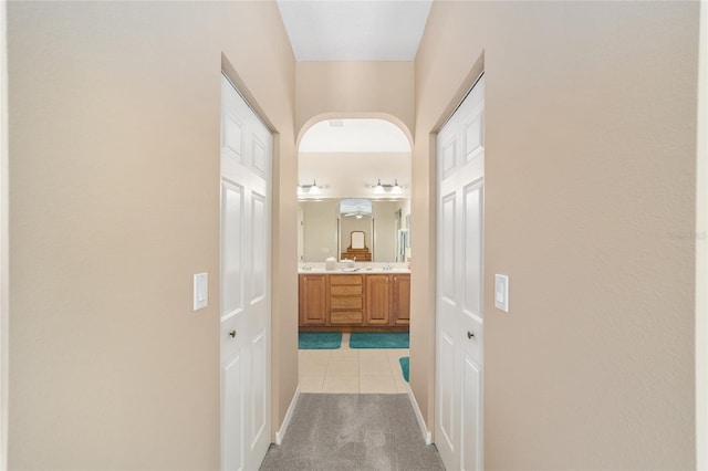 hall with light colored carpet and sink