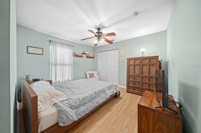 bedroom with ceiling fan, a closet, a textured ceiling, and light hardwood / wood-style flooring