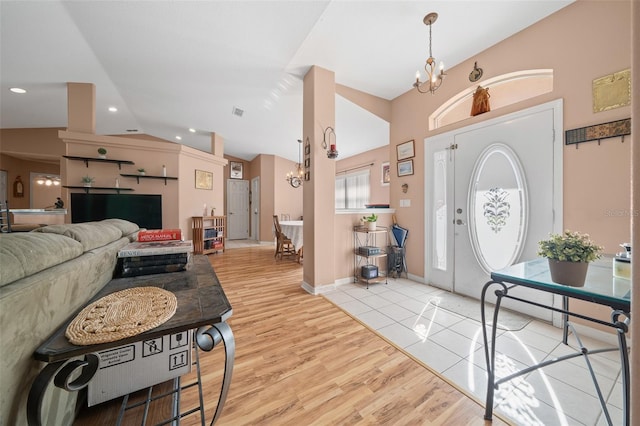 entrance foyer featuring light hardwood / wood-style floors, vaulted ceiling, and a notable chandelier