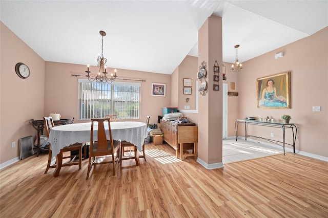 dining area featuring lofted ceiling, light wood-type flooring, and an inviting chandelier