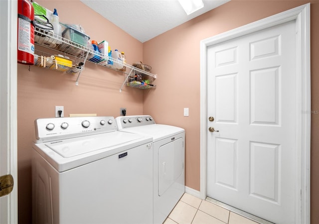 laundry room with light tile patterned floors, washer and dryer, and a textured ceiling