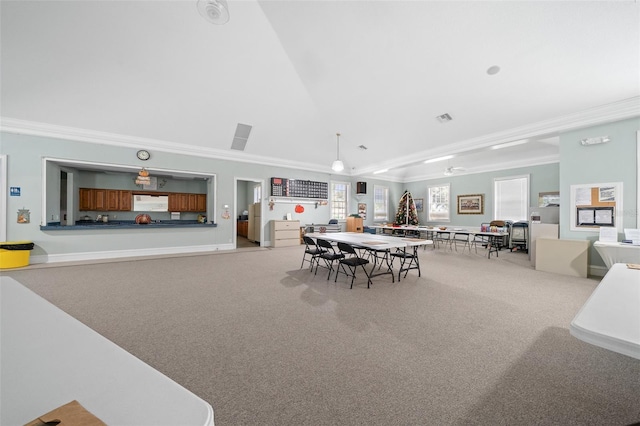 carpeted dining room with lofted ceiling and crown molding