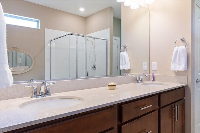 bathroom with dual sinks, large vanity, and a shower with shower door