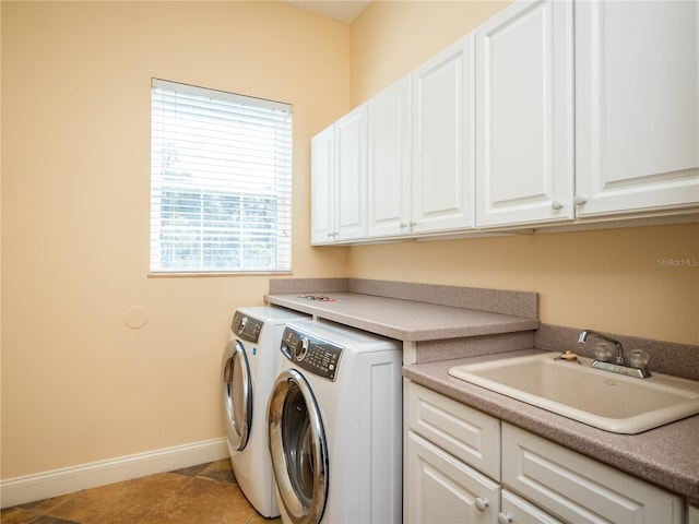 washroom with light tile patterned floors, washing machine and dryer, sink, and cabinets